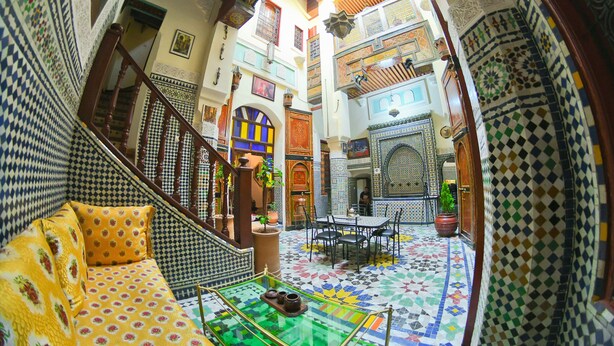 A traditional Moroccan interior with a staircase, patterned tiles, and a dining area. - Riad Dar Fes (Fes)
