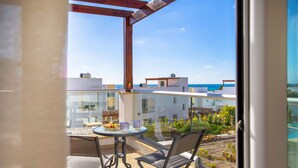 A balcony with a table and chairs, overlooking a residential area and the sea. - Villa Porto (Pegeia)