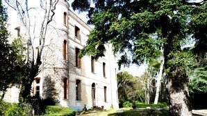A historic building with multiple windows and a well-maintained garden with trees and hedges. - La Bouriette (Moussoulens)