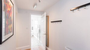A hallway with a door leading to a bathroom, a coat rack, and a radiator. - The New Kent Road Apartments (London)