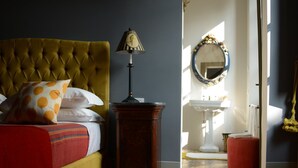 Een slaapkamer met een gestoffeerd hoofdeinde, een bedlampje en een bed met opdruk-kussens.