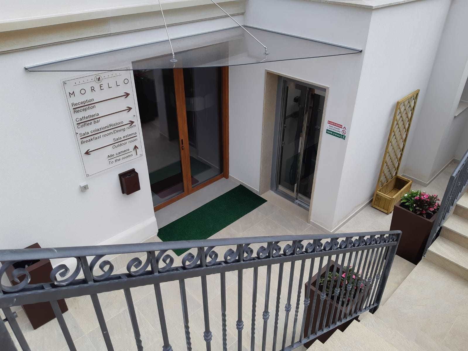 Zona de recepción de hotel con indicaciones hacia la recepción, el comedor, la sala exterior y otras instalaciones.