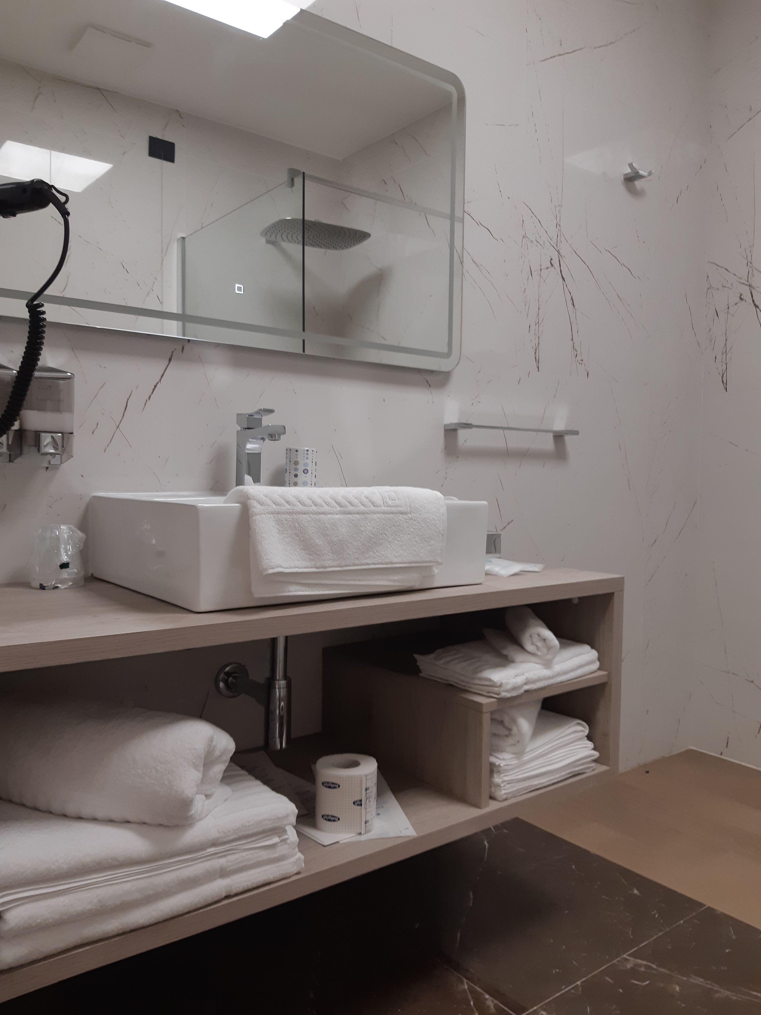 Een moderne badkamer met een wit wastafelmeubel, spiegel en handdoekenkast.