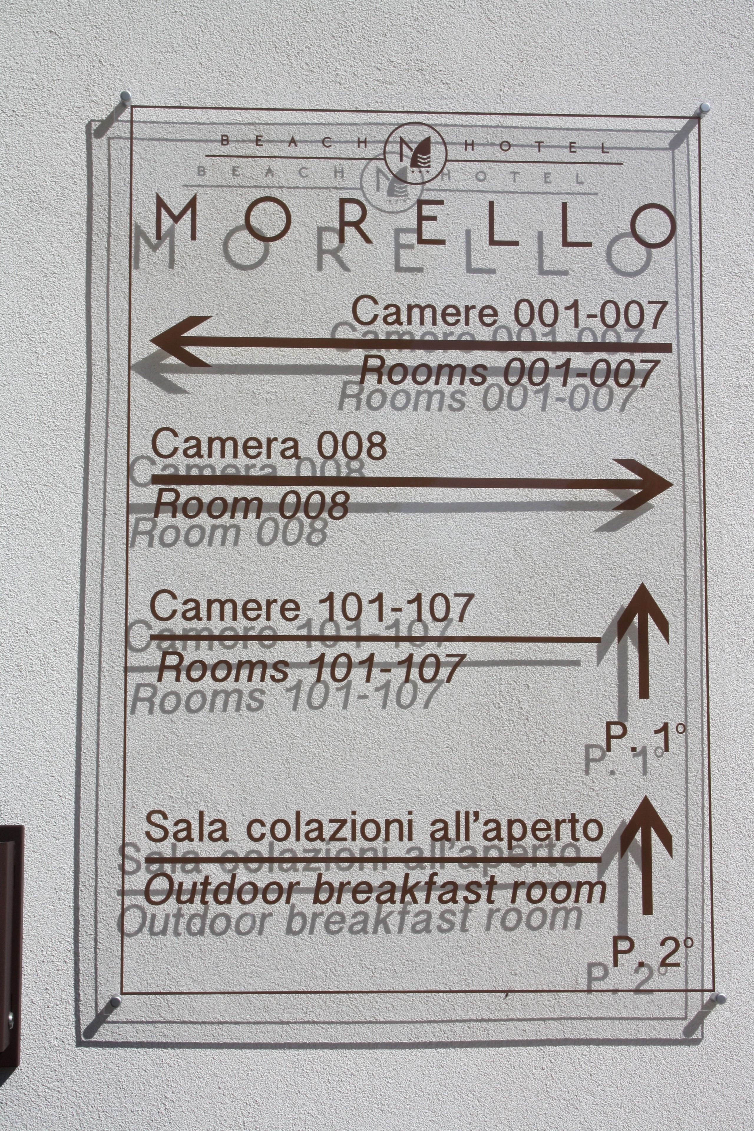 A hotel sign with directions to various rooms and amenities, including camera and room numbers, and an outdoor breakfast room.