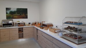 Une cuisine moderne dotée d’un barbecue intégré, d’un comptoir-buffet proposant divers plats et d’un tableau accroché au mur.