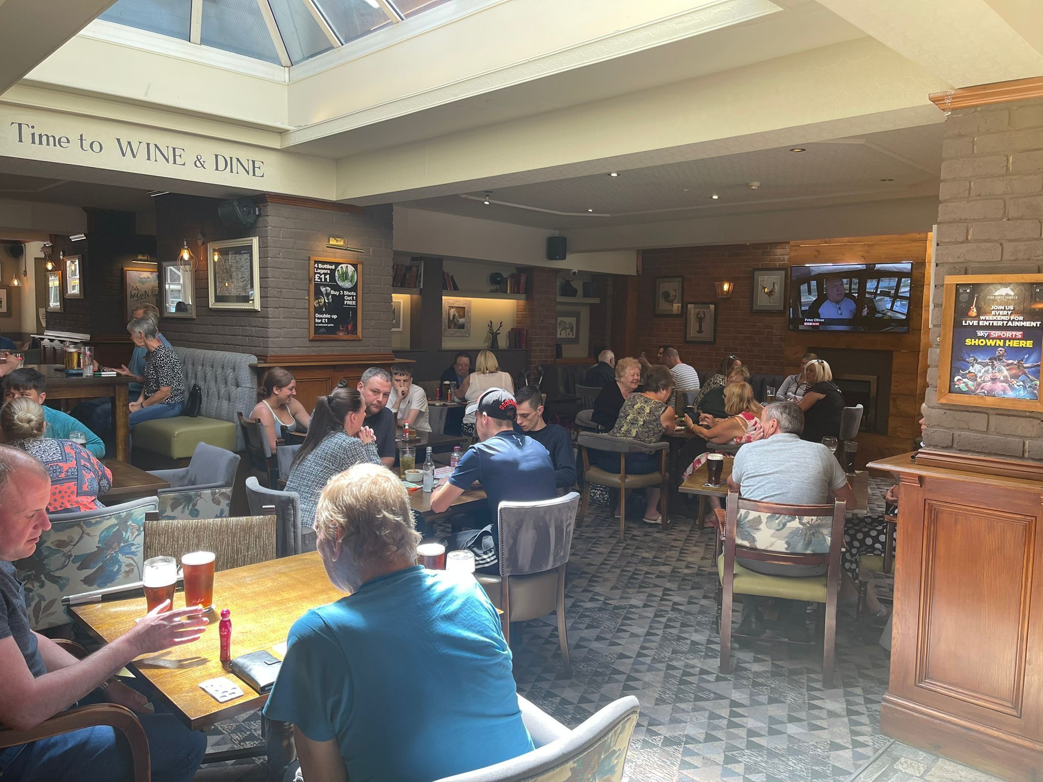 A restaurant with a high ceiling, brick walls, and a variety of seating options including tables and booths.
