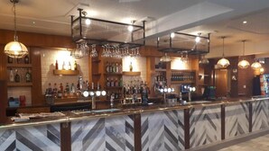 A bar area with a chevron-patterned counter, hanging lights, and shelves of liquor bottles. - The Grey Horse (Darlington)
