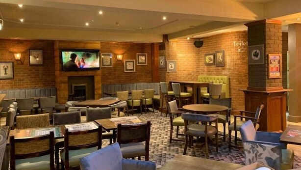 A cozy lounge area with multiple seating options, a television, and a fireplace. - The Grey Horse (Darlington)
