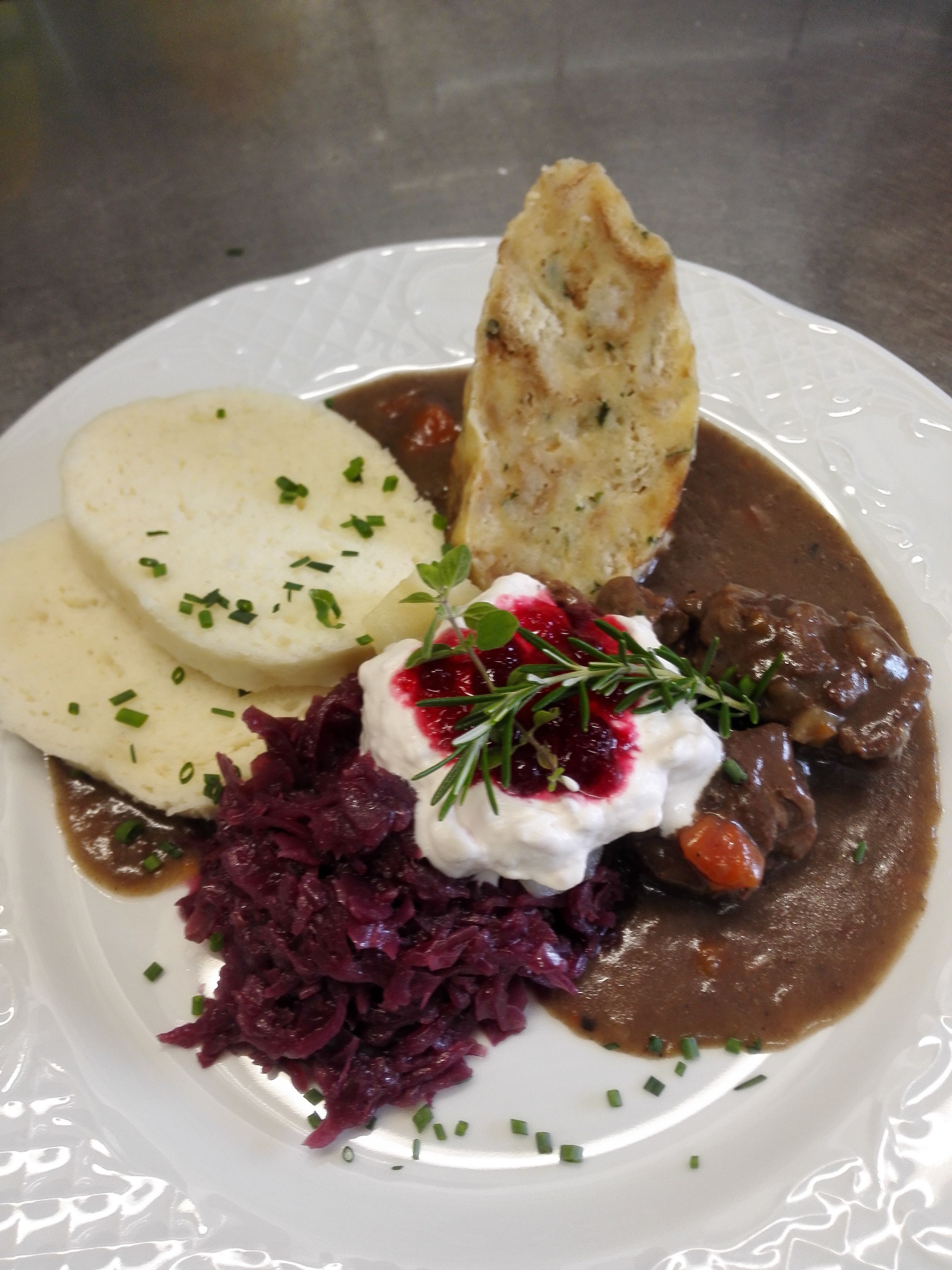 A plate of food with a meat dish, mashed potatoes, and red cabbage.