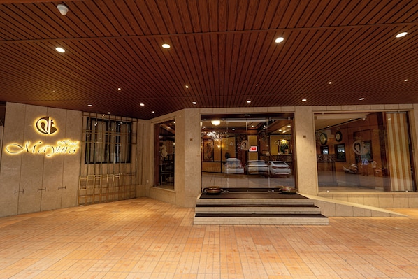 A hotel entrance with a wooden ceiling, a neon sign, and a tiled floor. - Hotel Mayura (Raipur)