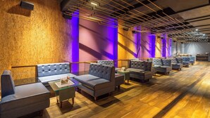 A modern lounge with leather sofas and glass tables, wooden flooring, and a ceiling with exposed beams and lighting. - Hotel Mayura (Raipur)