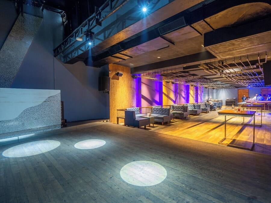 Un espacio amplio con escenario, zona de estar y bar.