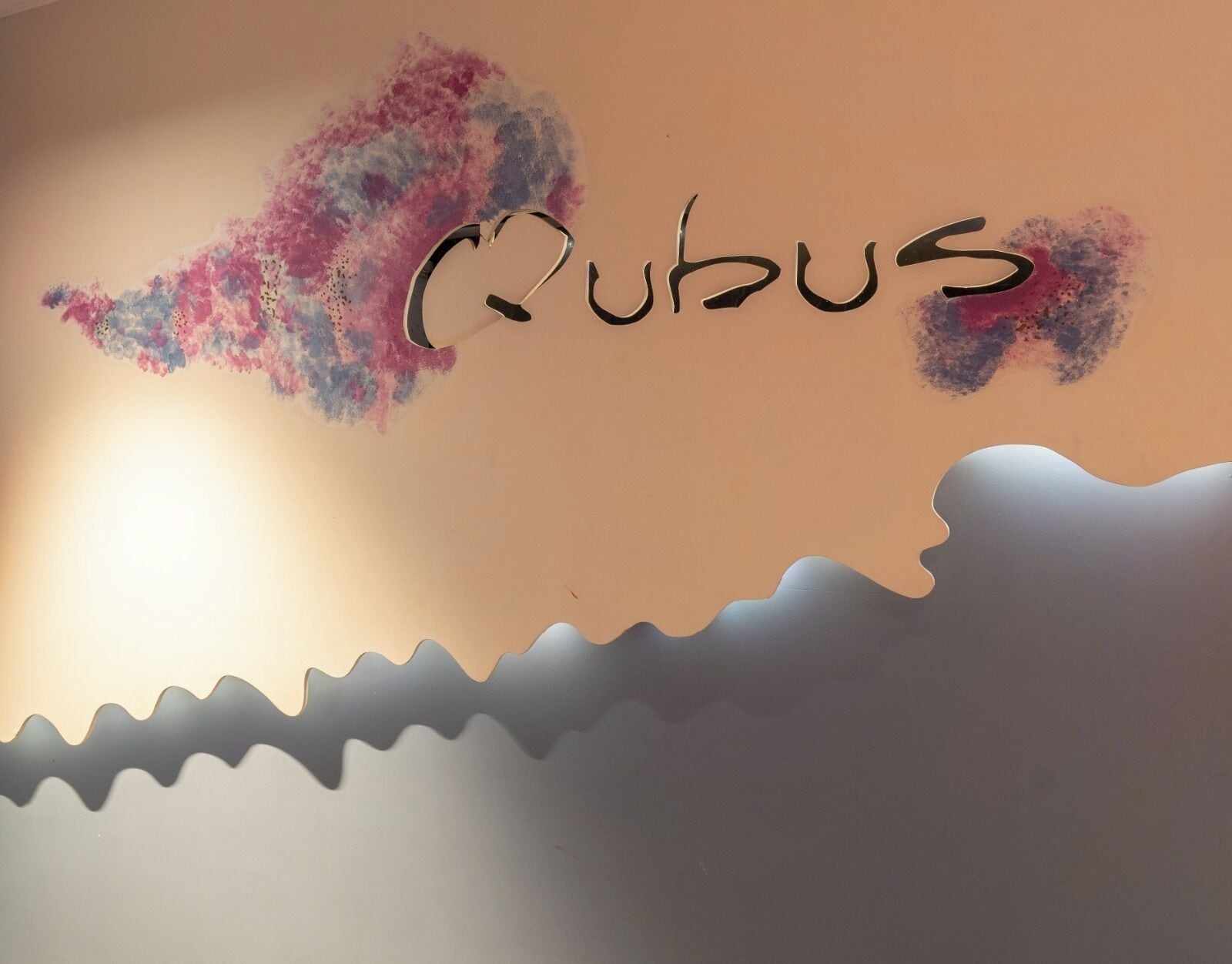 Una pared con la palabra 'Rubus' en una tipografía estilizada, una pintura abstracta y colorida, y el silueta de un rostro.