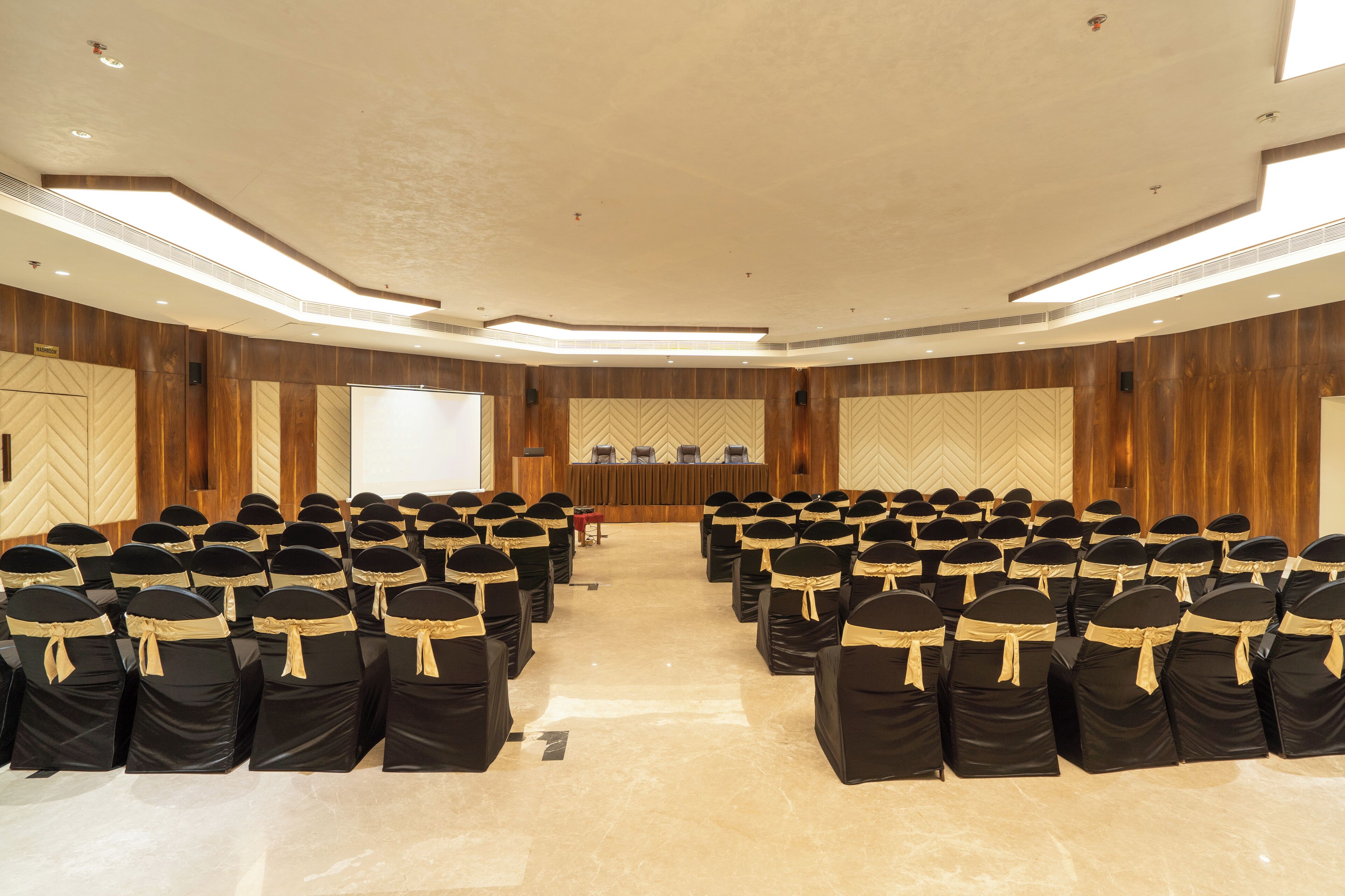 A conference room with rows of chairs, a podium, and a projection screen.