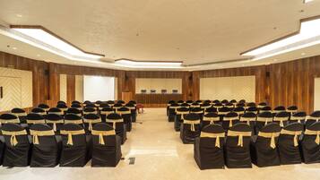 A conference room with rows of chairs, a podium, and a projection screen.