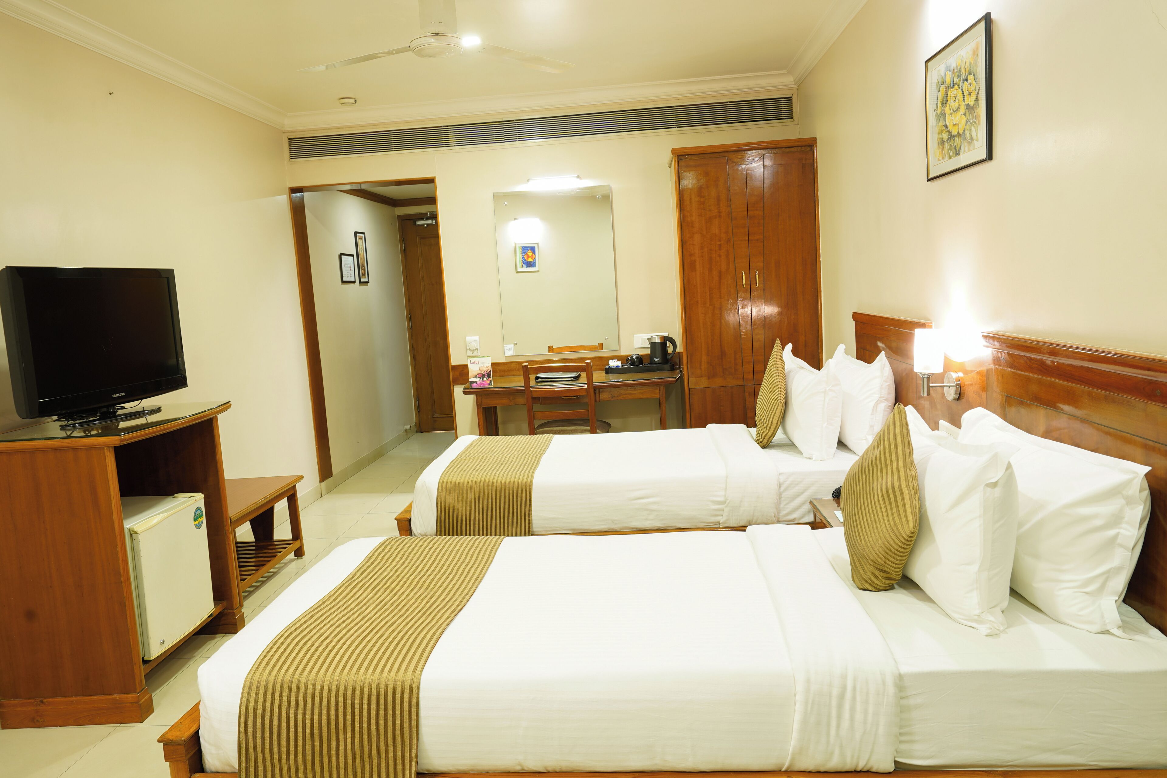 A hotel room with two beds, a television, a desk, and a wardrobe.