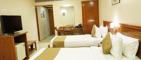 A hotel room with two beds, a television, a desk, and a wardrobe.
