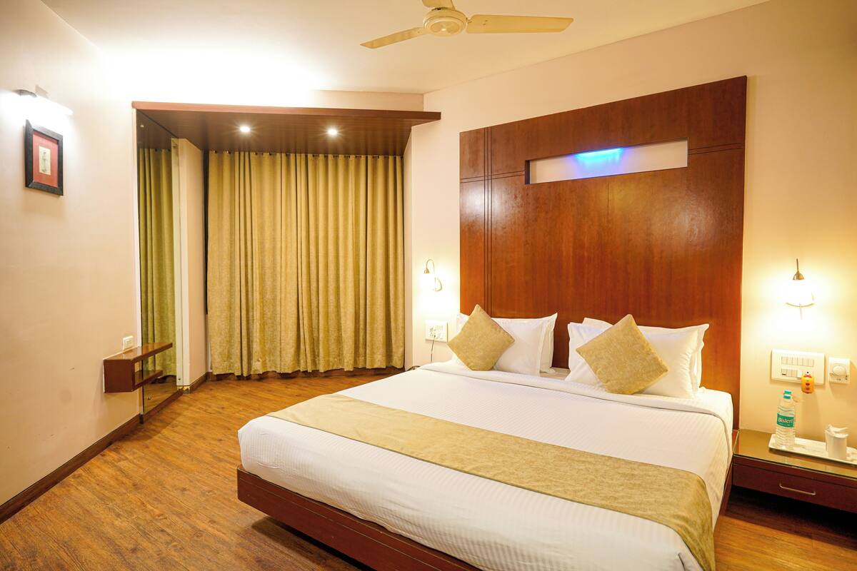 A hotel room with a large bed, wooden headboard, bedside lamps, and a mirror.