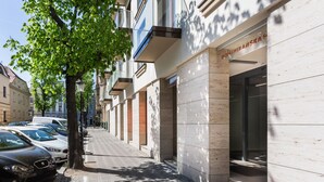 Uma fileira de edifícios modernos com uma calçada arborizada e carros estacionados.