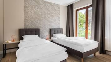A modern hotel room with two single beds, a nightstand, a lamp, and a window with curtains.