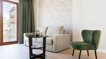 A modern living room with a sofa, a green armchair, a small table with a plant, and a patterned wall.
