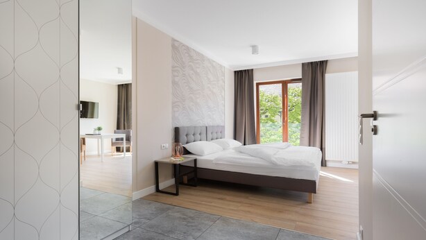 Quarto moderno com uma cama grande, uma mesa de cabeceira e vista para uma área de jantar.