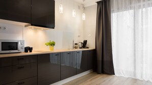 Cozinha moderna com armários escuros, micro-ondas, máquina de café e luminárias pendentes.