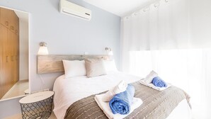 A hotel room with a bed, bedside lamps, a mirror, and a window with curtains. - Villa Siena (Pegeia)