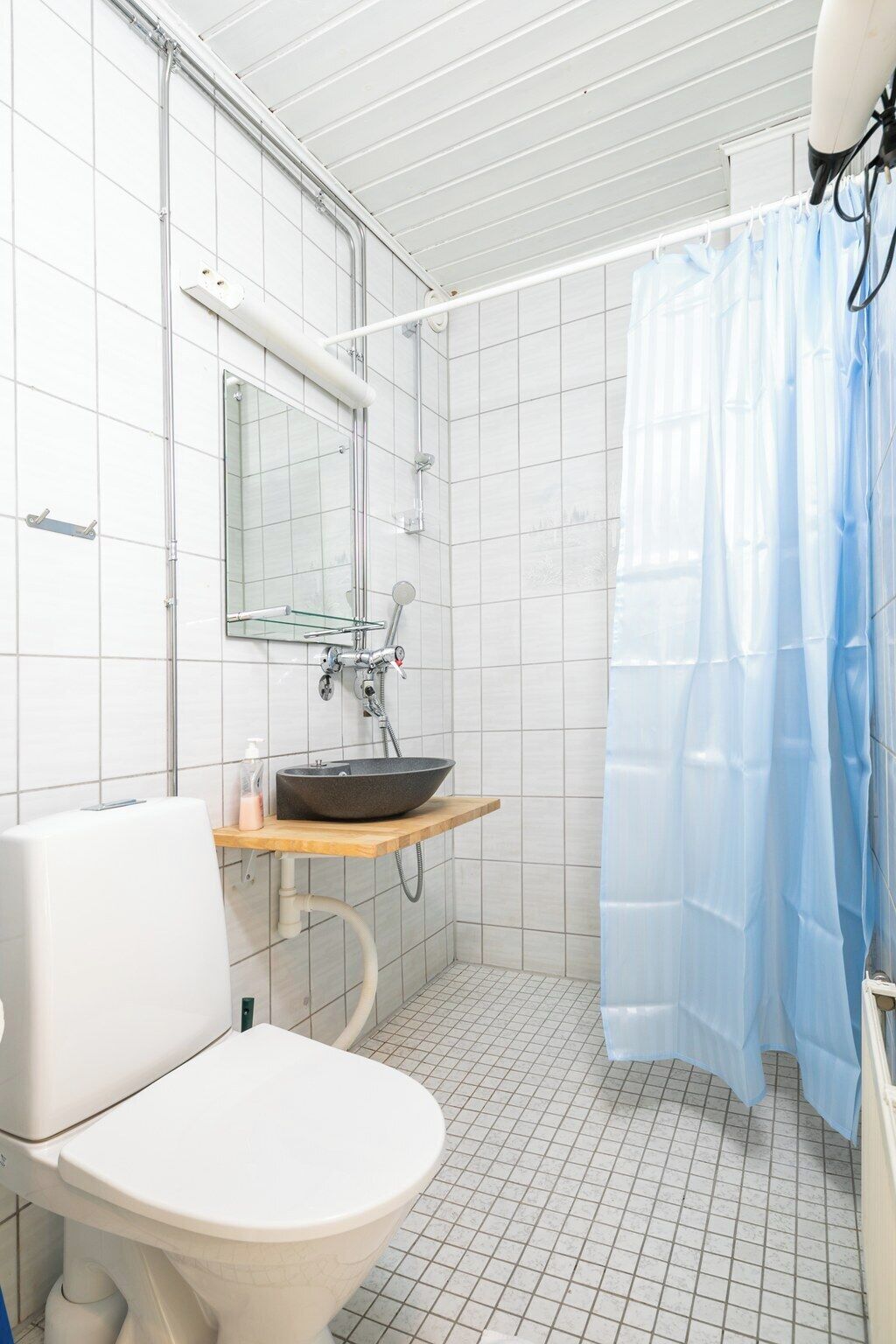Ein Badezimmer mit Toilette, Waschbecken, Spiegel und Duschvorhang.