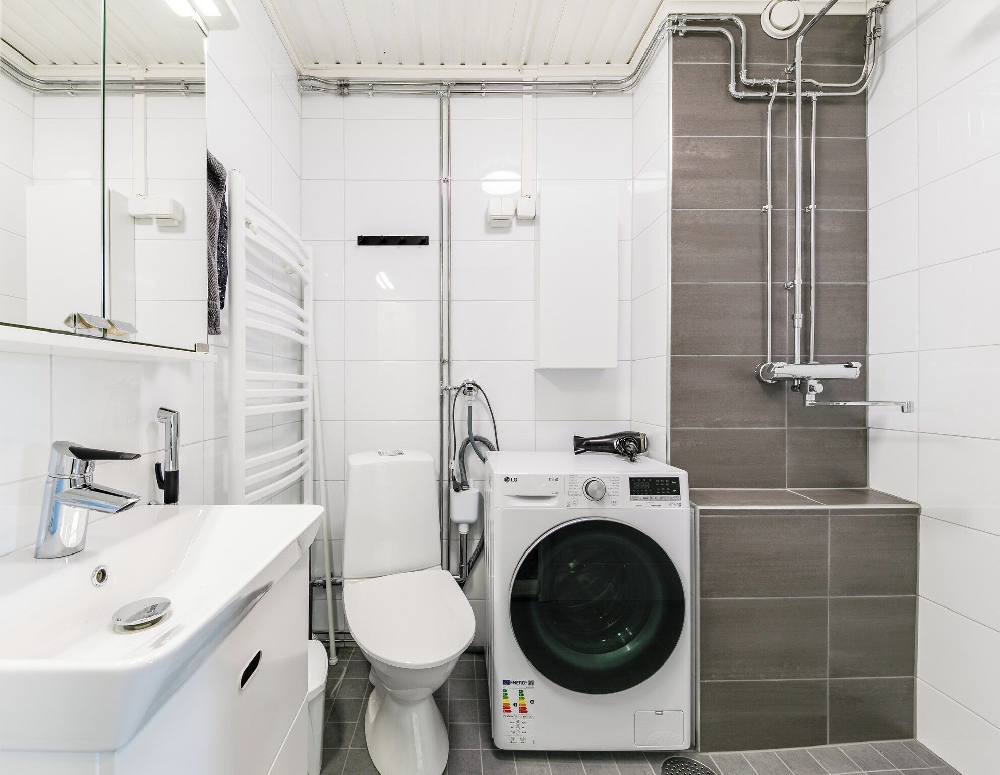 Un baño moderno con lavamanos, inodoro y lavadora integrada.