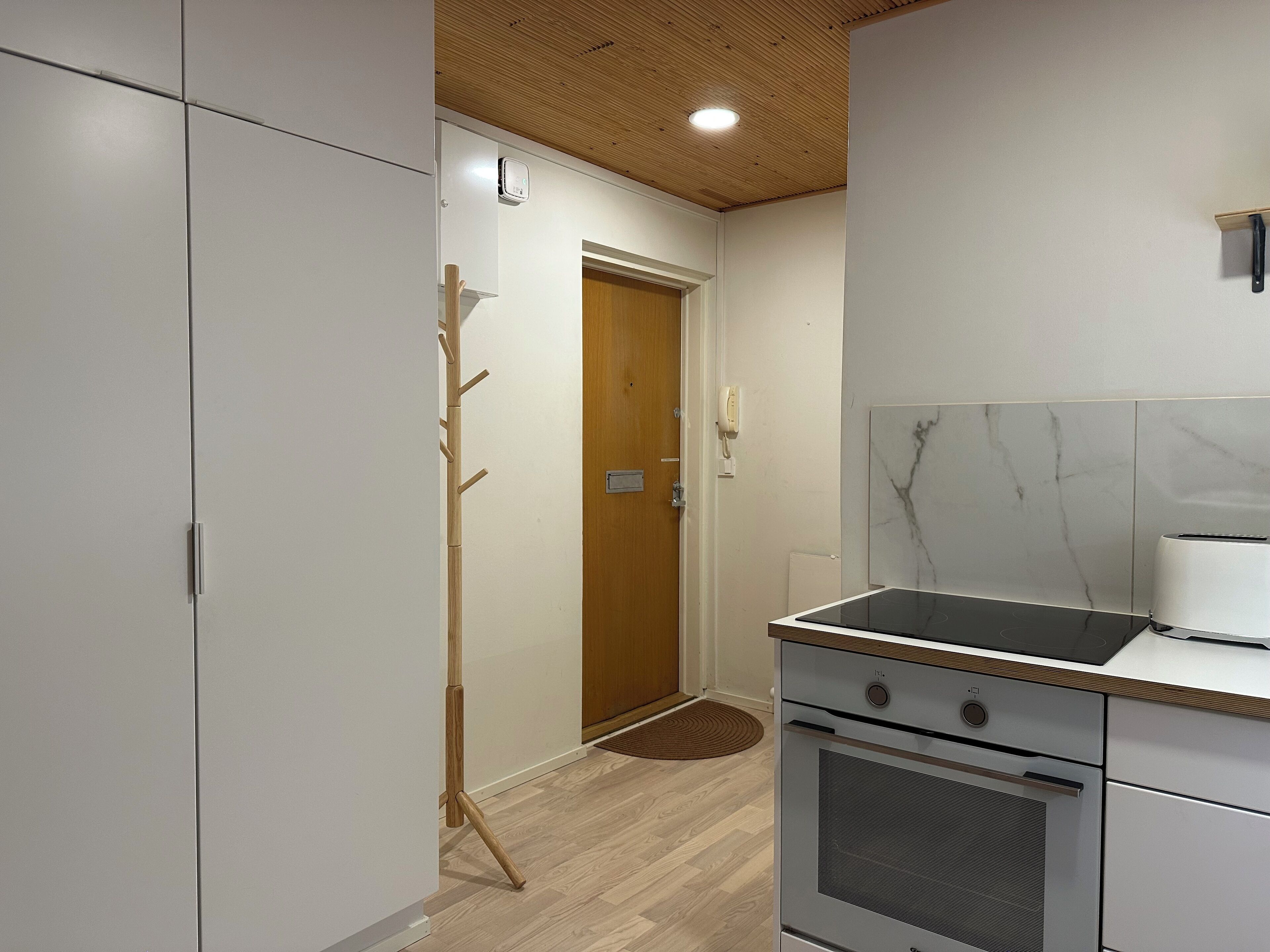 Una cocina moderna con horno integrado, un perchero de madera y techo de madera.