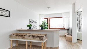 A modern kitchen with a wooden bench, white walls, and a window with sheer curtains. - Santa's Holiday Homes (Rovaniemi)