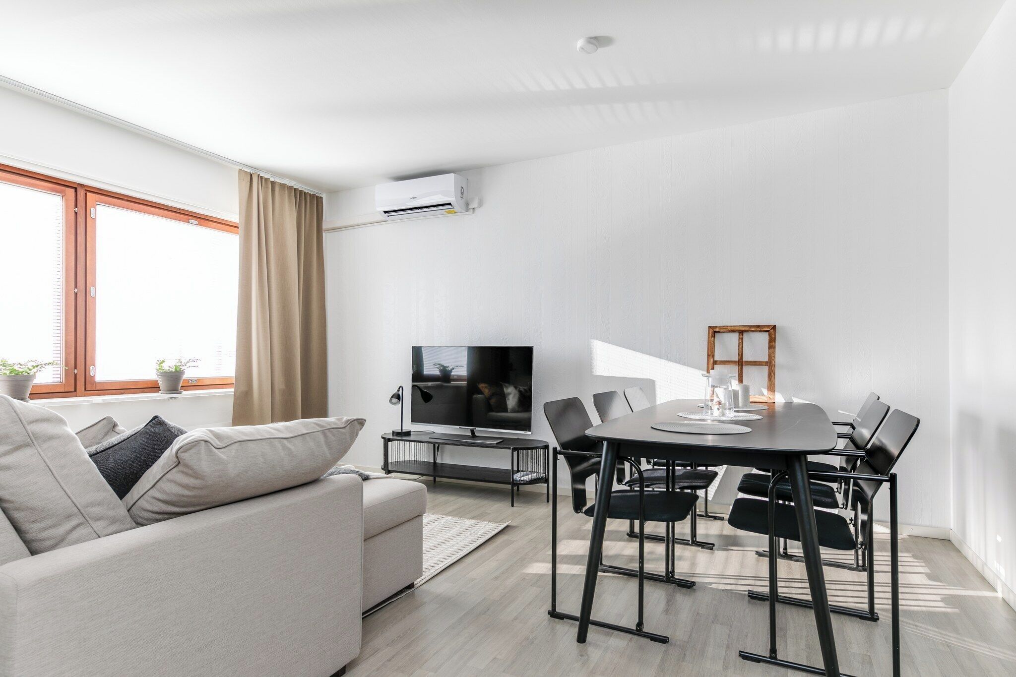 Un salon moderne comprenant un canapé, un téléviseur, une table à manger et des chaises.