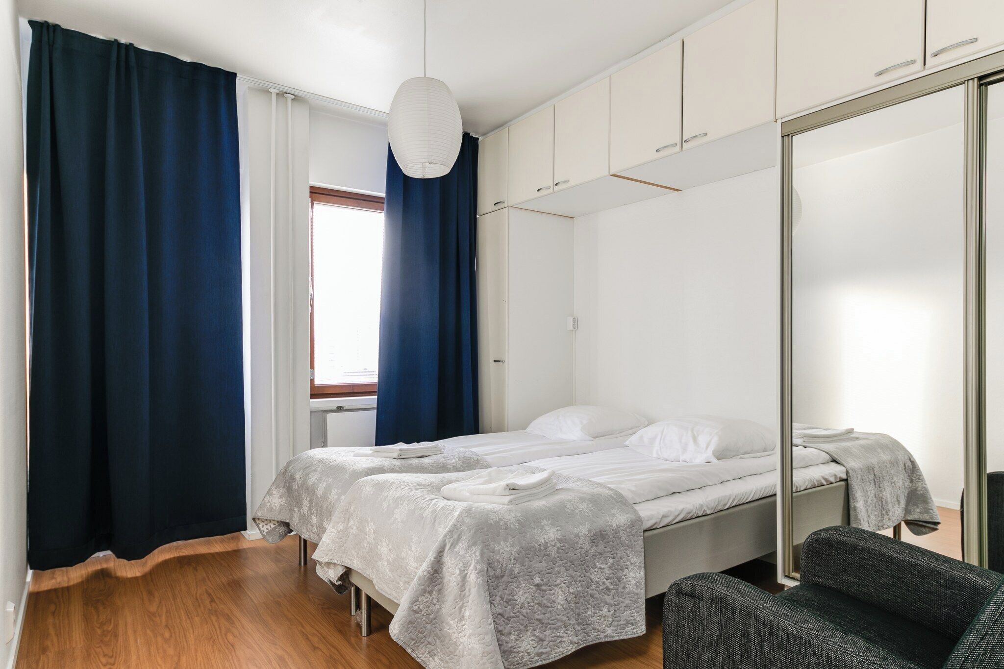 Ein Schlafzimmer mit zwei Betten, einem großen Spiegel und einem Sessel.