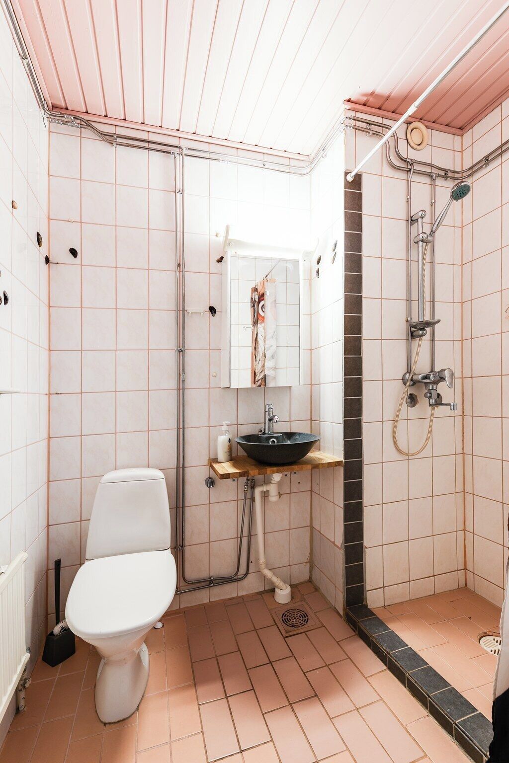 Un baño pequeño con inodoro, lavamanos y ducha.