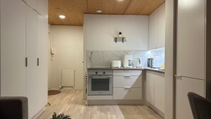 A modern kitchen with a central island, built-in oven, and white cabinetry. - Santa's Holiday Homes (Rovaniemi)