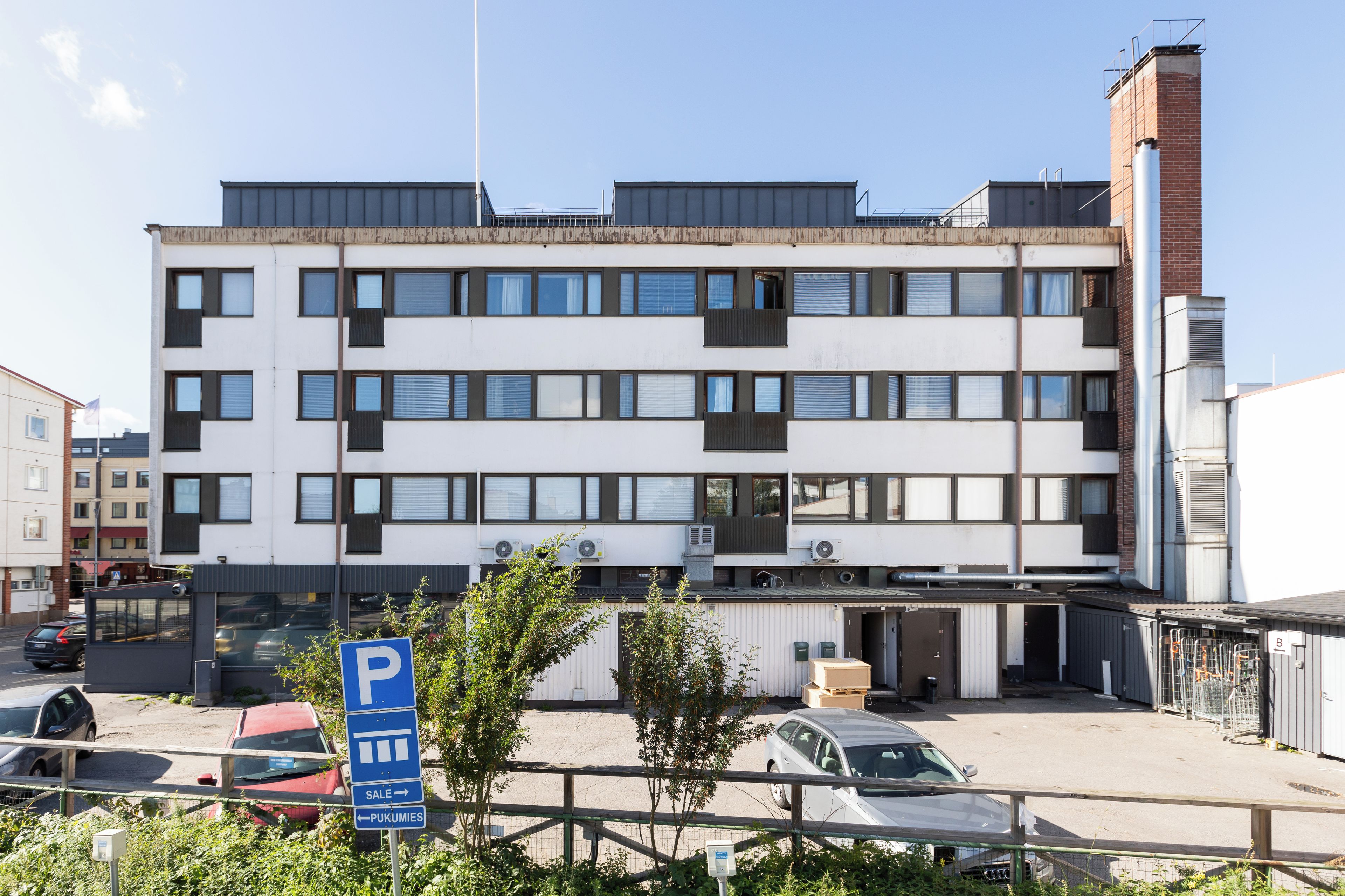Un edificio de varios pisos con un área de estacionamiento al frente.