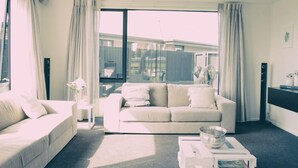 A modern living room with a sofa, a coffee table, and a large window with curtains. - Relax In True New Modern Style (Christchurch)