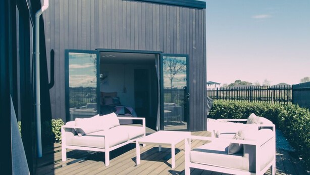 An outdoor deck with white furniture, including sofas and a table, and a glass door leading to an interior space. - Relax In True New Modern Style (Christchurch)