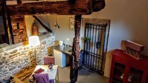 A rustic kitchen with stone walls, a wooden beam ceiling, a hanging light, and a red cabinet. - Tenuta Edonè Agriturismo (Graniti)