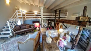 A rustic interior with a loft bed, a sofa, a dining table, and a staircase. - Tenuta Edonè Agriturismo (Graniti)