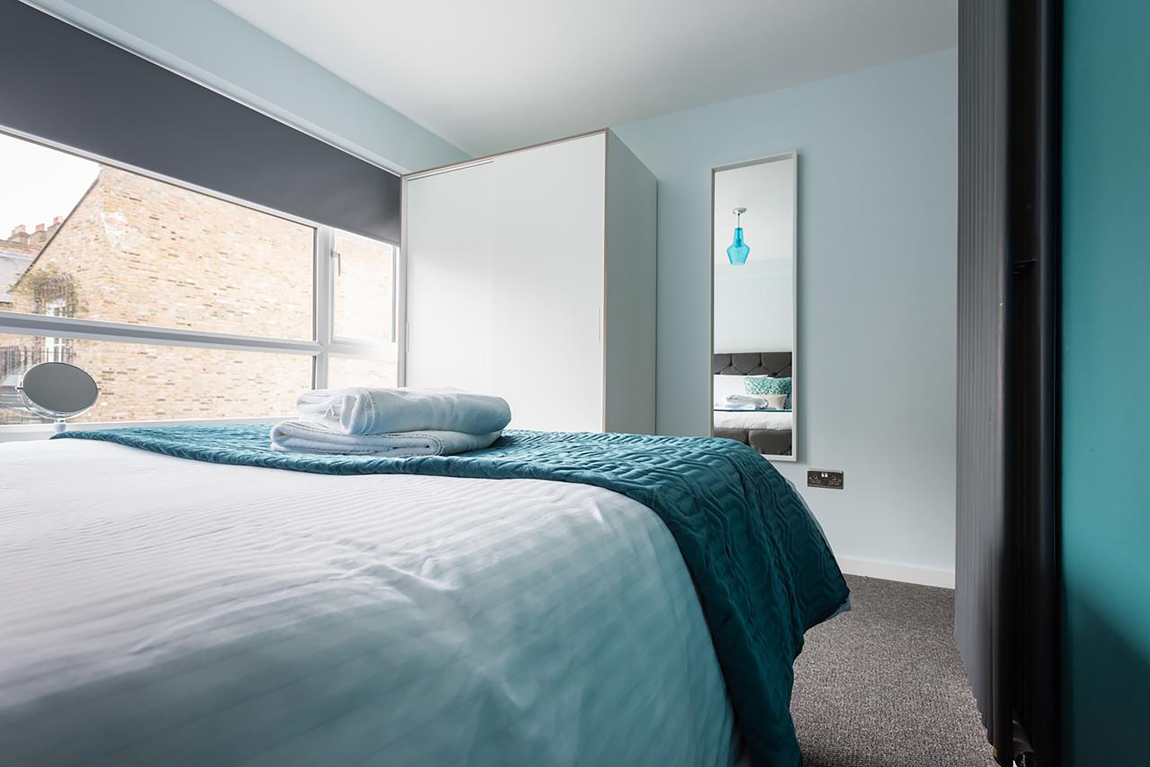 Quarto moderno com uma cama grande, uma janela, um espelho e vista para o exterior.