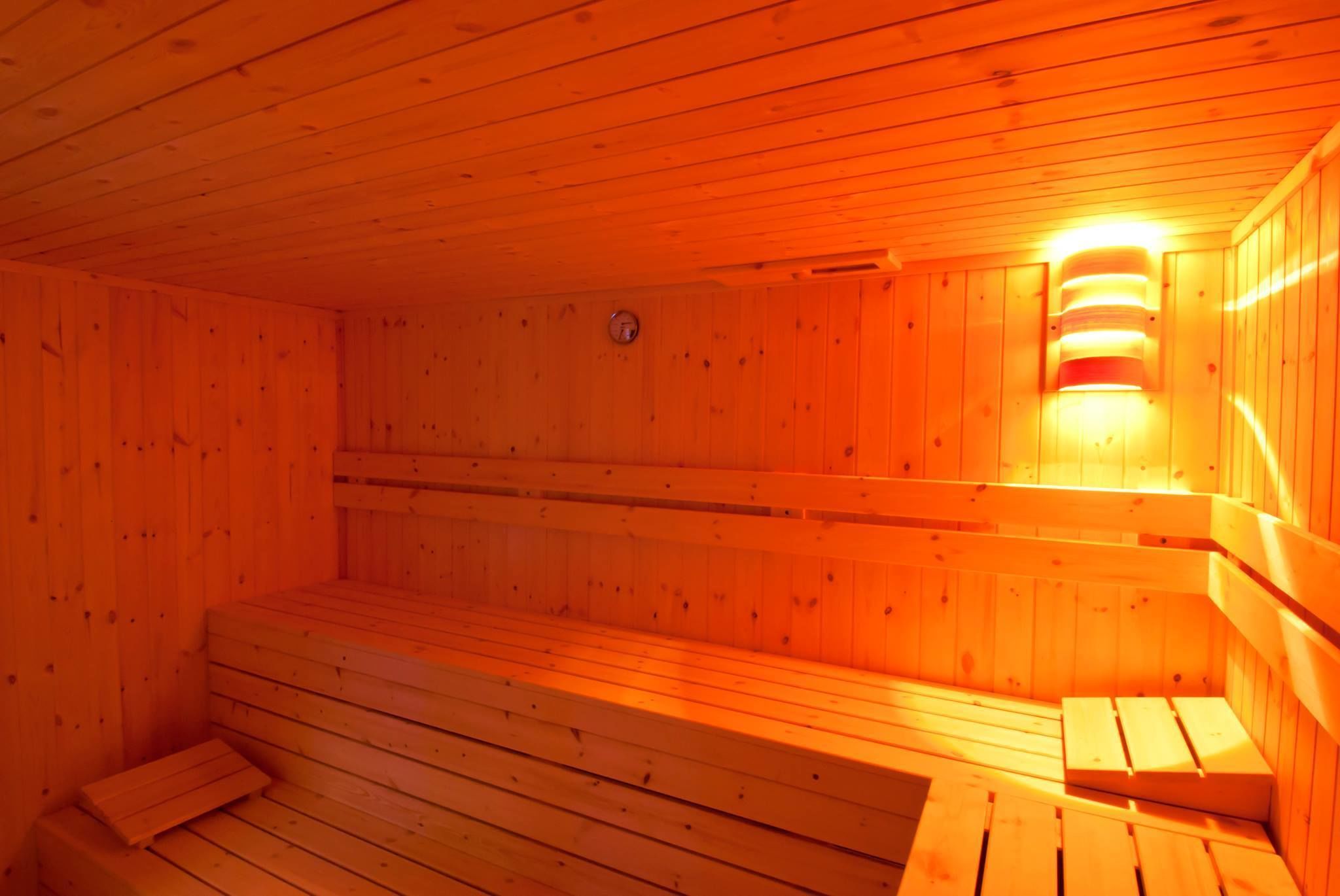 Un sauna avec des bancs en bois et un luminaire fixé au mur.