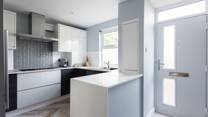 A modern kitchen with white cabinets, a built-in stove, and a window providing natural light. - The Nine Elms Residence (London)