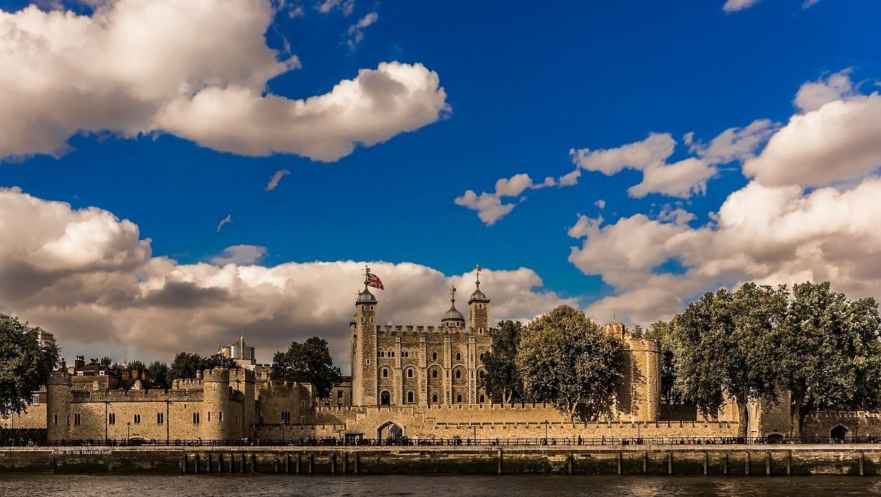 Um castelo histórico com uma torre imponente, localizado às margens de um rio.