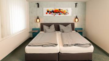 A double bed with two nightstands, a wall-mounted abstract painting, and a window with blinds.