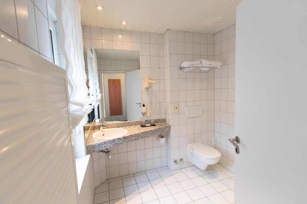 Ein modernes Badezimmer mit Waschbecken, Spiegel, Toilette und Handtuchhalter.