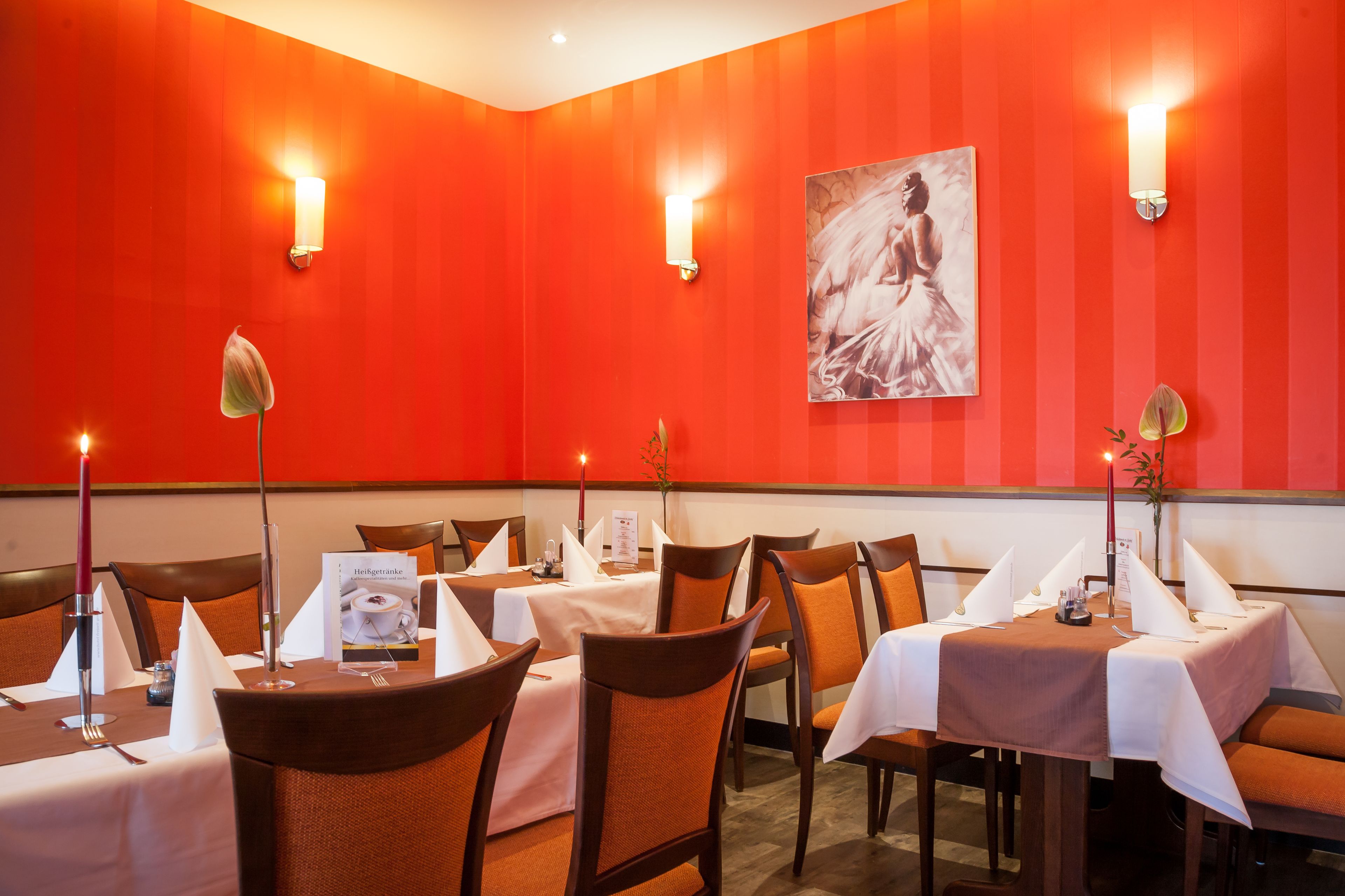 A restaurant with red walls, white tablecloths, and orange chairs.