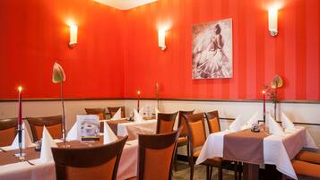 A restaurant with red walls, white tablecloths, and orange chairs.