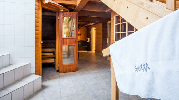 L’intérieur d’un chalet en bois comprend un espace sauna, un escalier en bois et un plancher carrelé.